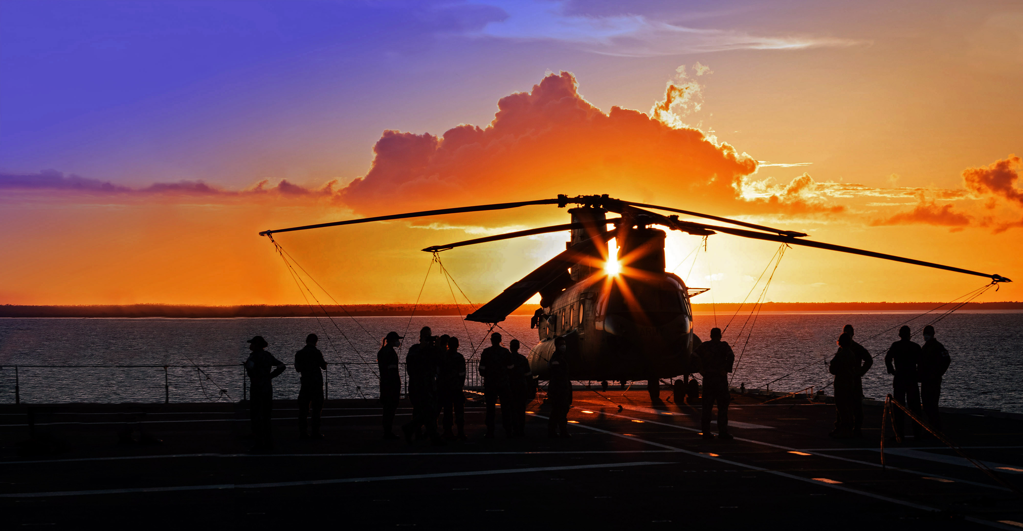 helicopter on an army ship with dramatic sunset background